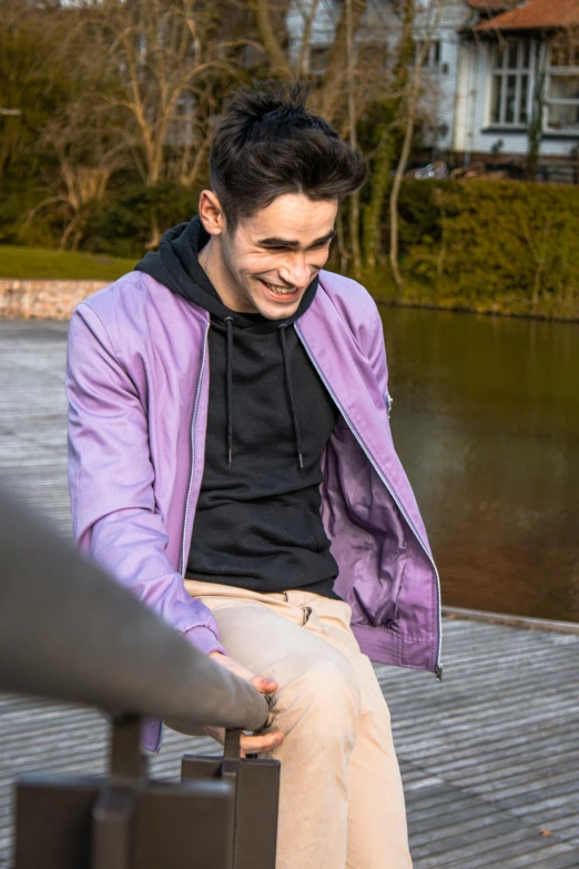 man in blue jacket smiling sitting on bench