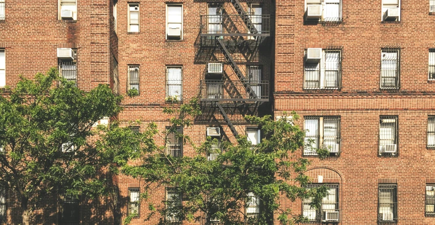 several windows on a tall brick building with a fire escape