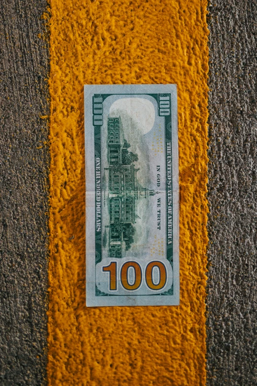 a hundred dollars bill with yellow stripe painted on it