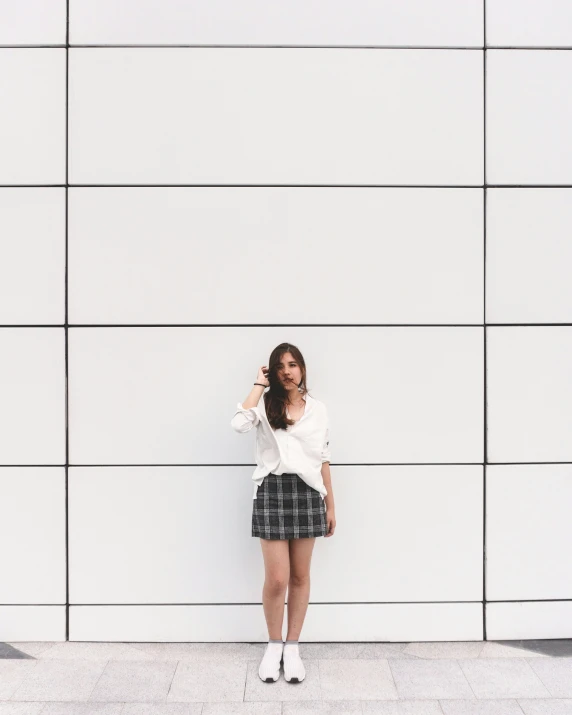 a woman wearing short hair posing next to a white wall