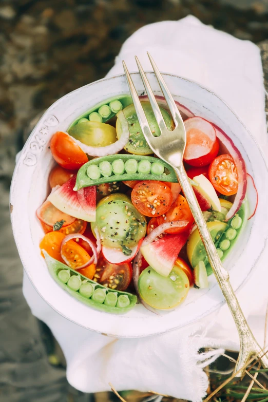 a white bowl of vegetables with a fork