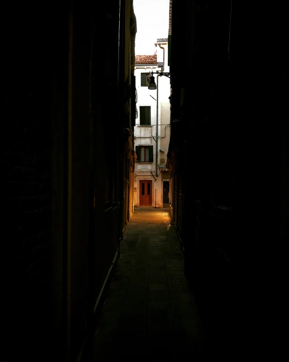 a narrow alley way with a small apartment building seen at night