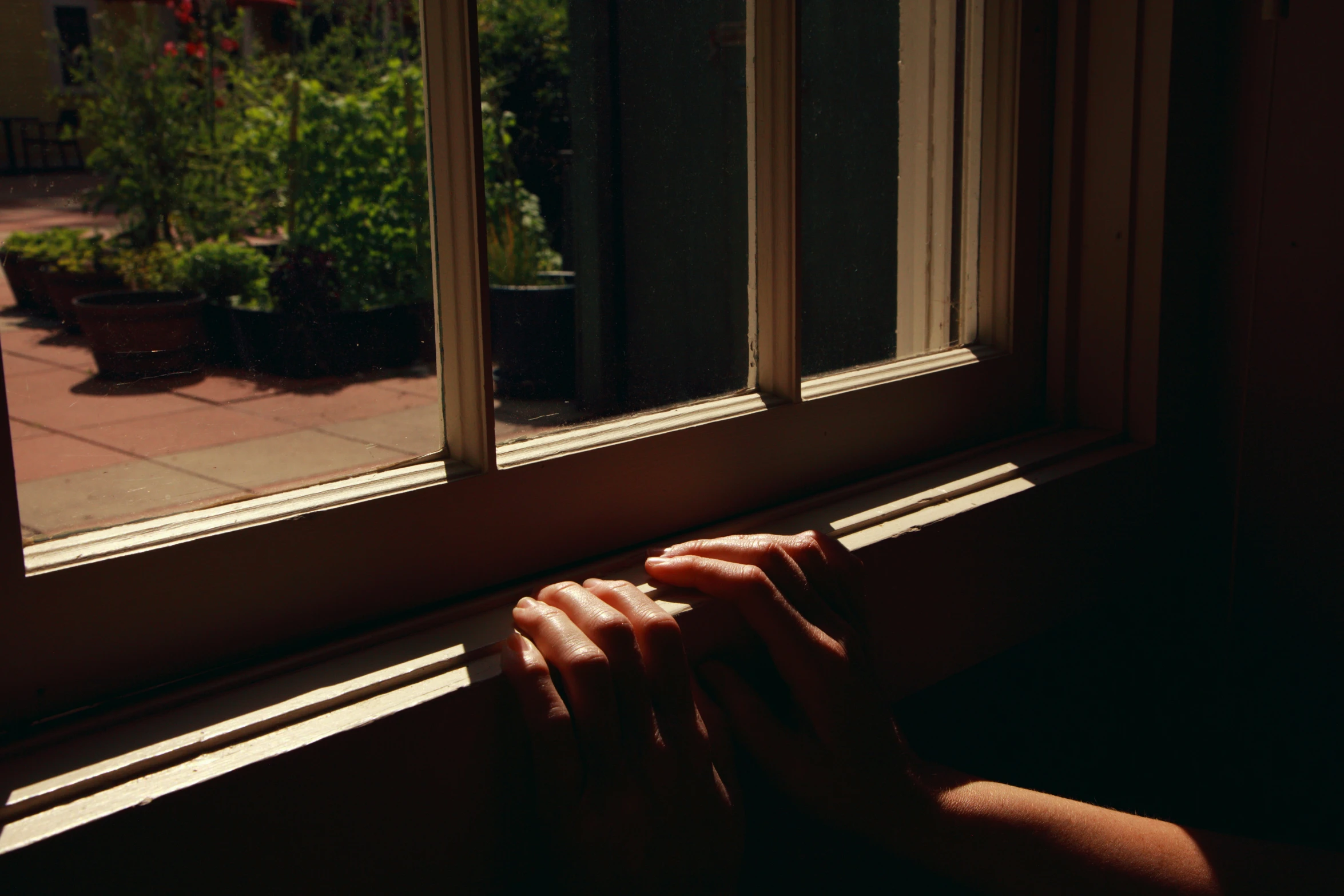 hand resting on the window ledge by the window