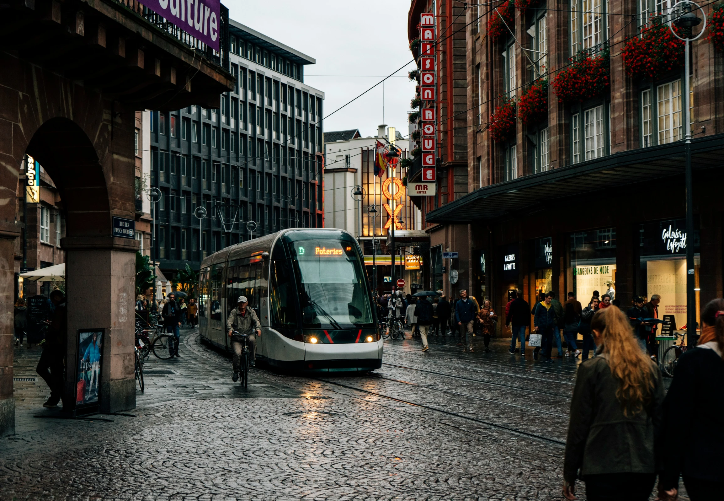 a bus driving past an old building on a rainy day