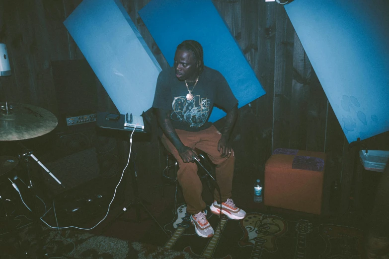 a man sits on a stool in a dark room next to a laptop