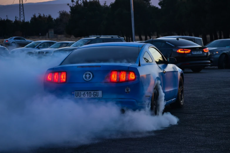 a mustang drifts out of the lot as it blows up smoke