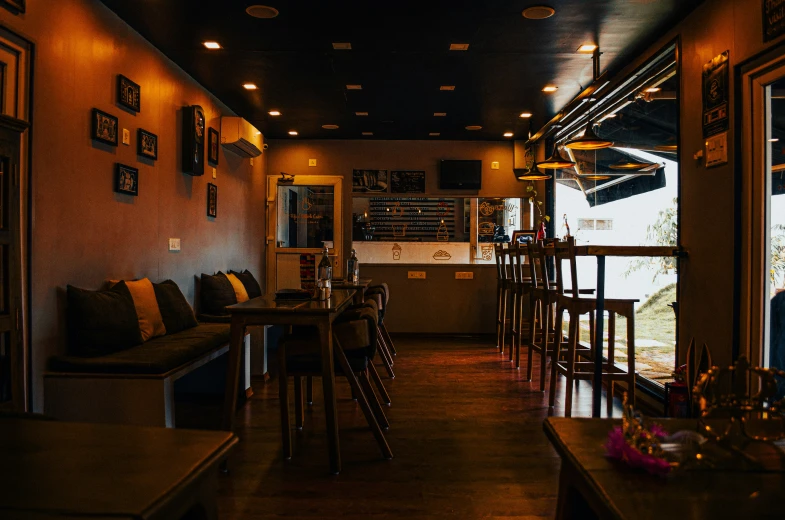 dark lighting a bar with wooden tables and some chairs