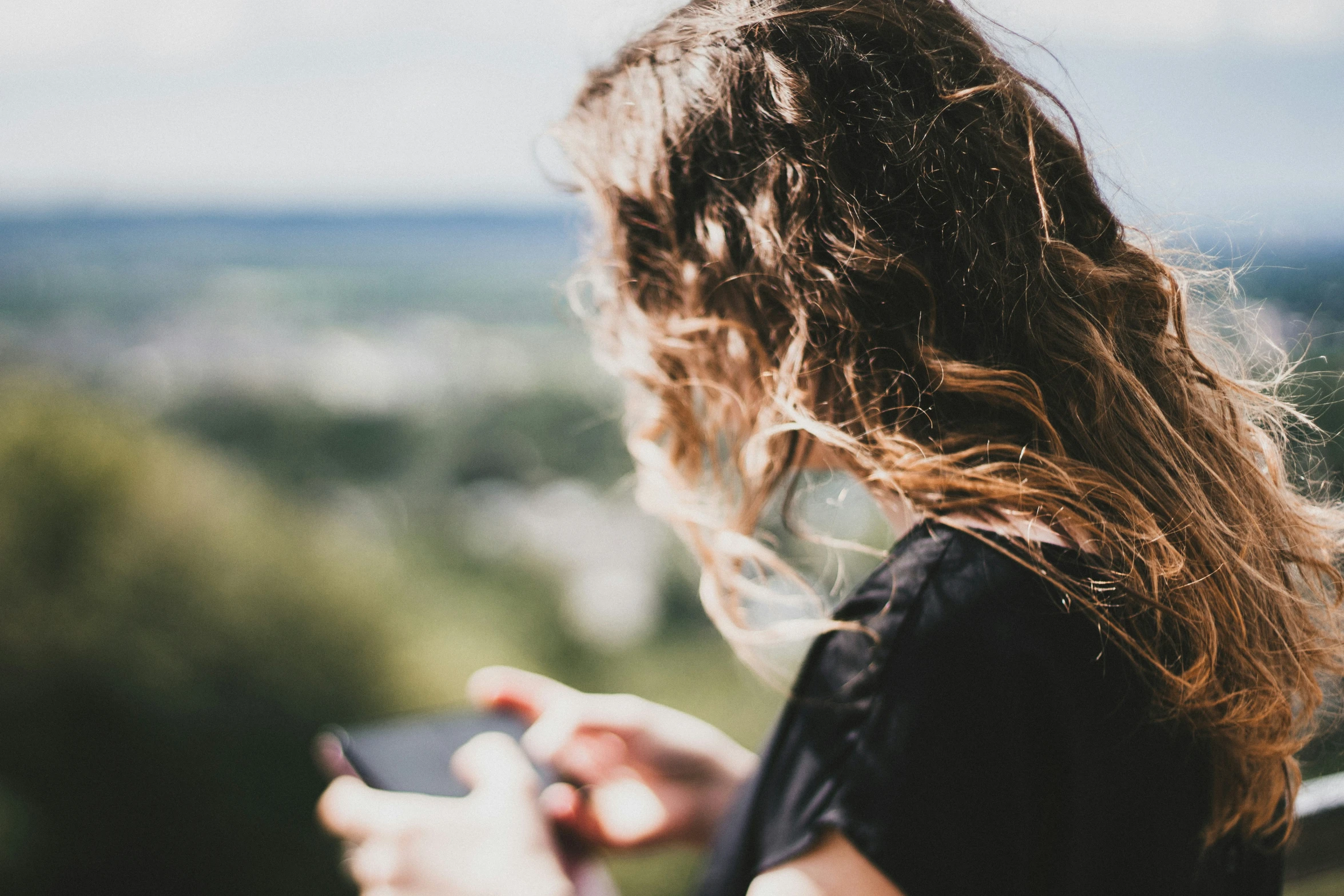 the woman is holding her cellphone while looking at it