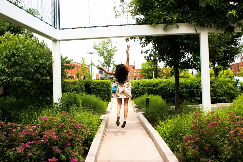 a woman walking down the sidewalk with flowers around her