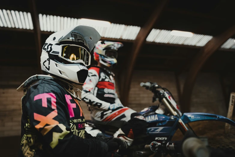 two people wearing helmets are sitting on motorcycles