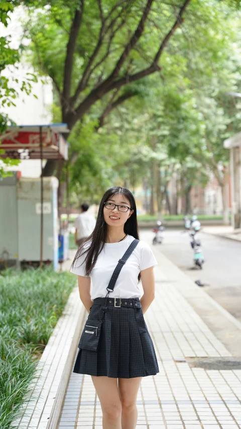 a girl wearing a white t - shirt, black miniskirt, black suspenders and black heels