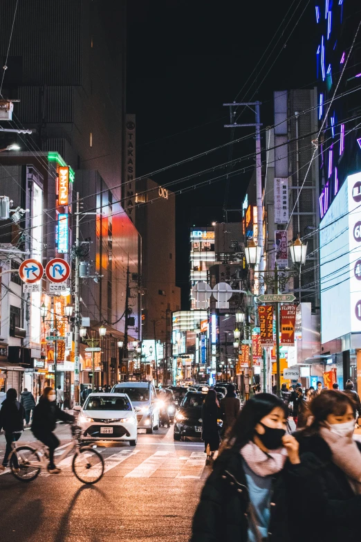 people walking and cars driving on a city street at night