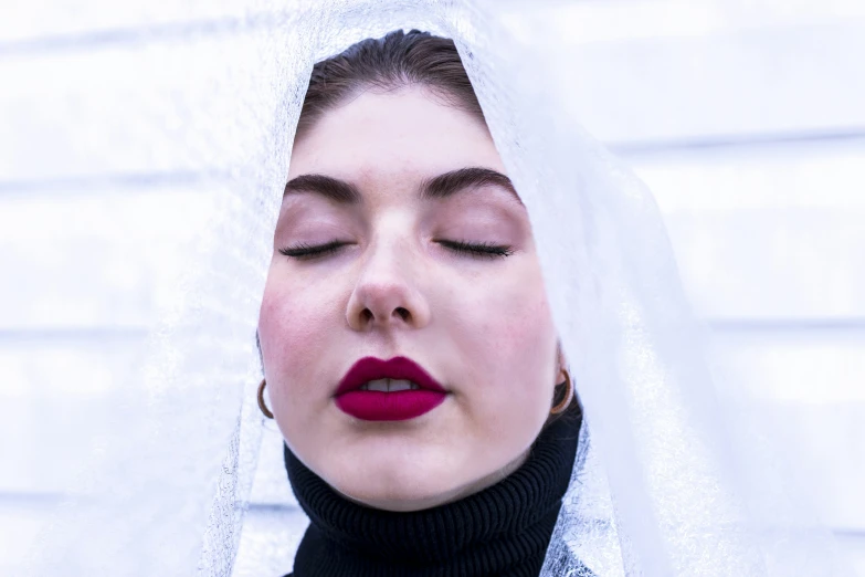 a woman with her eyes closed wearing a veil