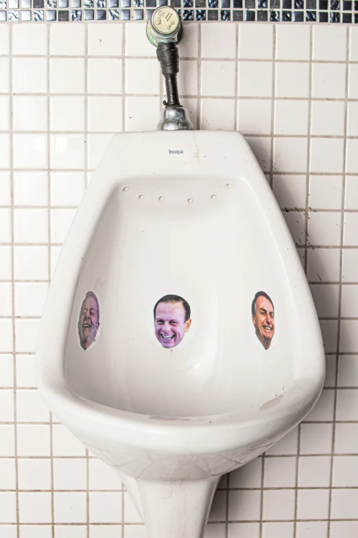 a urinal has the faces of three men on it