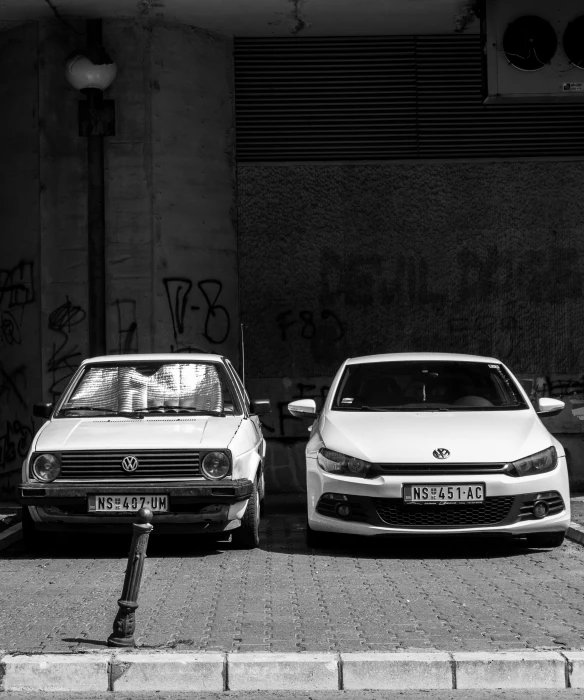 two parked cars sitting in the middle of a parking lot