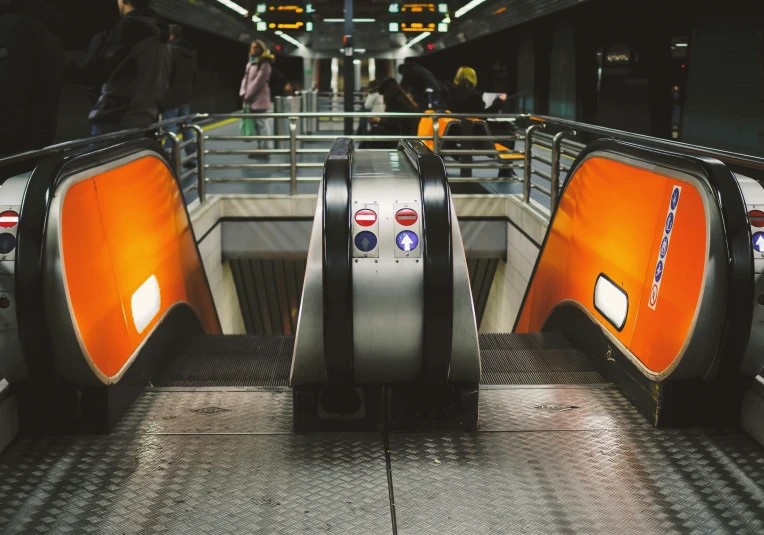 an escalator with orange paneling and metal railings