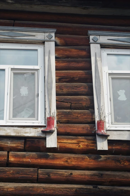 a pair of white windows in the side of a log house