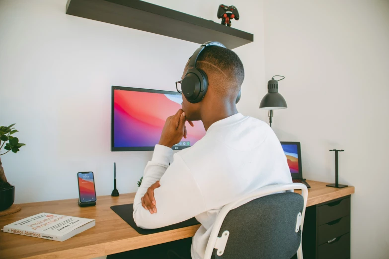 a man in a white hoodie sitting at a computer