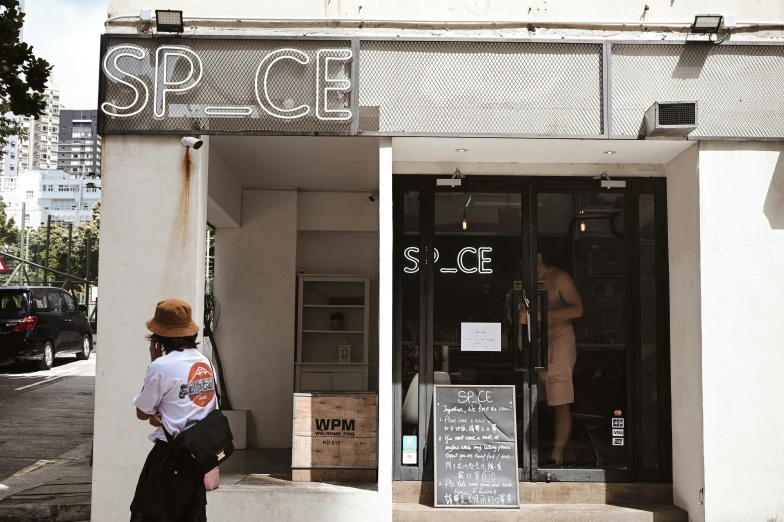 a person is standing outside of a shop with a sign above it