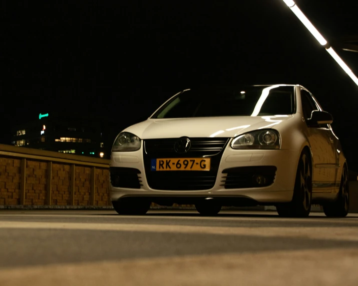 a white car parked in front of a wooden fence at night