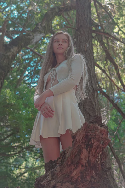 a woman standing up against a tree in the woods