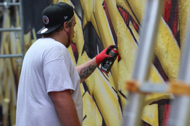 a man painting the side of a wall with a pair of scissors