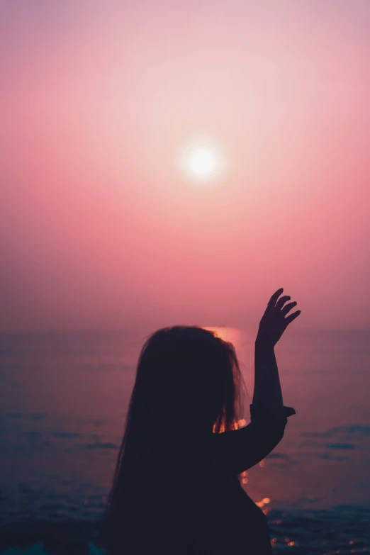 a person that is sitting down with her hands out to the sun