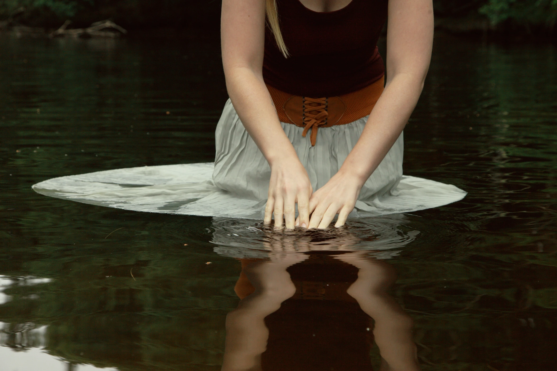 a beautiful woman kneeling down on top of a body of water