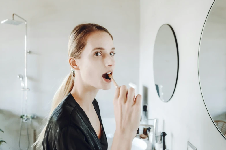 woman brushing her teeth in the bathroom mirror