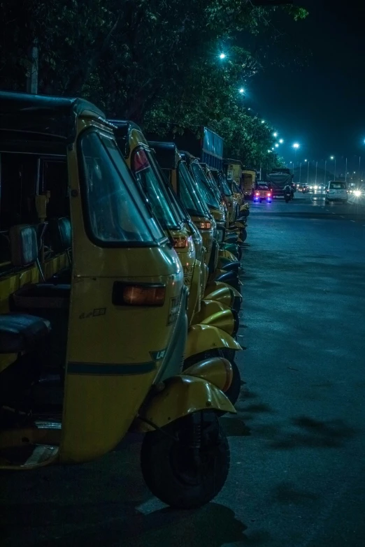 cars parked along the curb at night near trees