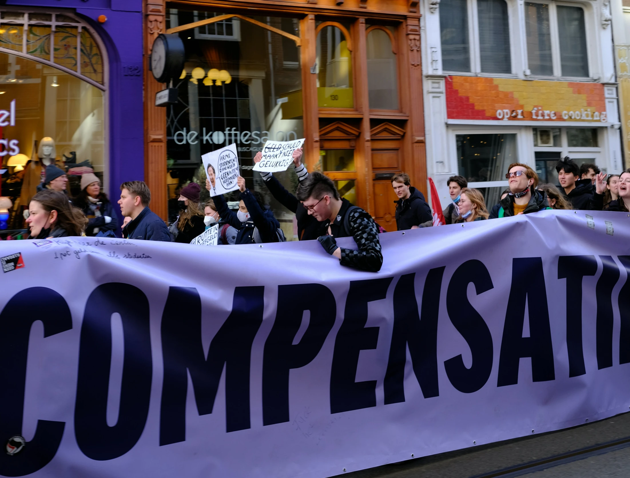 a crowd of people stand in front of a store, while one person holds up a sign that says compensata