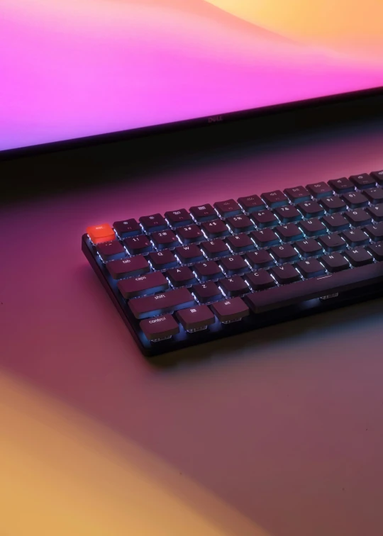 a remote control sitting on a purple surface next to a laptop