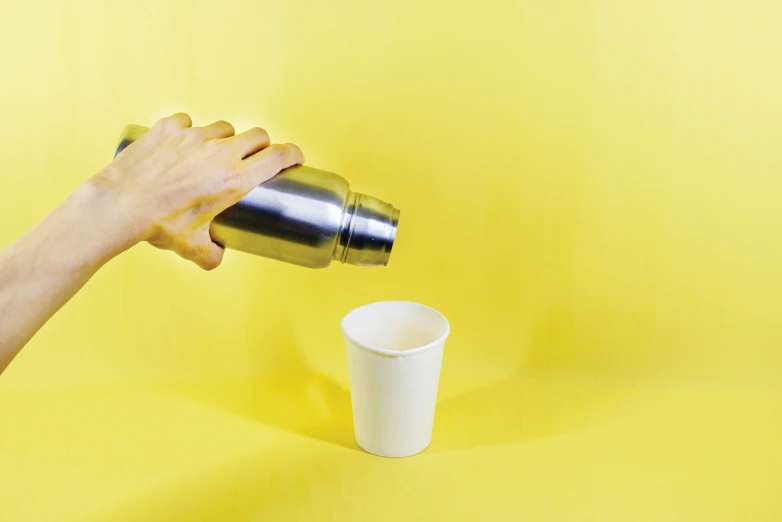 a person is grabbing a cup while a person is holding the top half of it