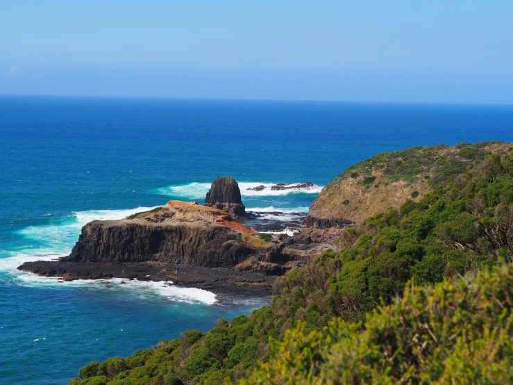 a small rock outcropping on a cliff with a lighthouse in the background