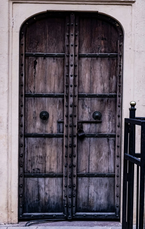 two brown wooden doors on a stone wall