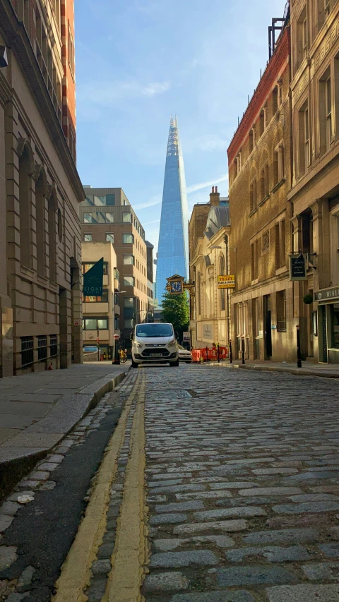 a vehicle on a narrow street near a city with tall buildings