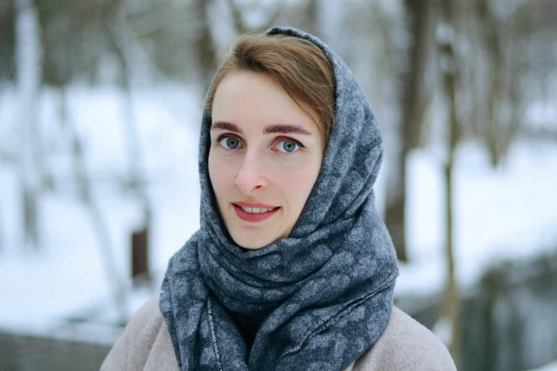 a woman with a scarf around her head and a snowy area behind her