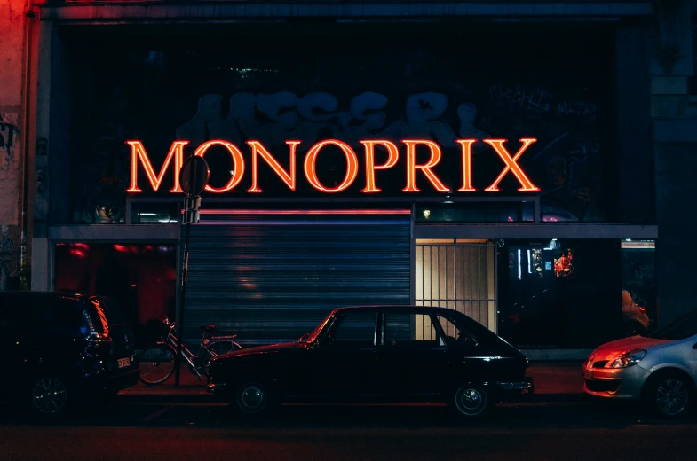 a neon sign that says monopolx above two vehicles