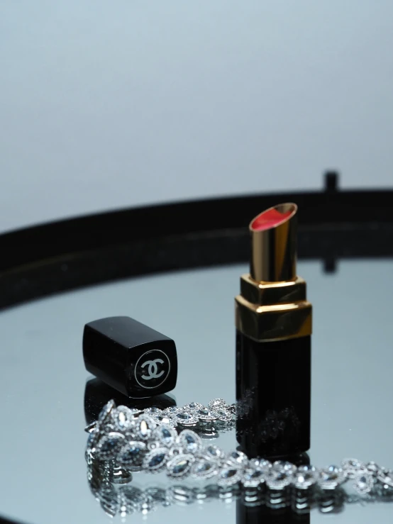 the lipstick is in its box, and next to a gold chain