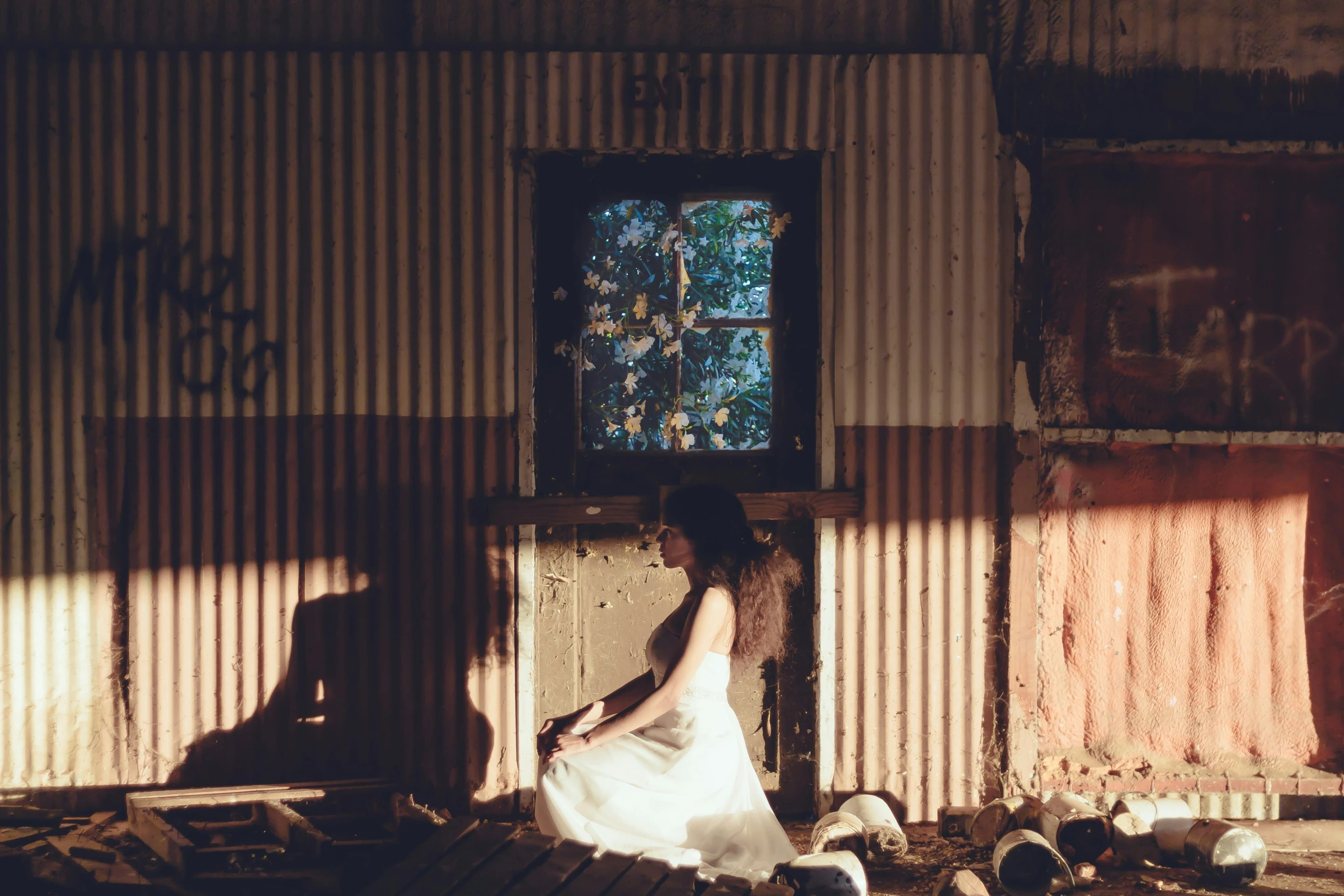 a woman kneeling in front of an open door on a brick wall