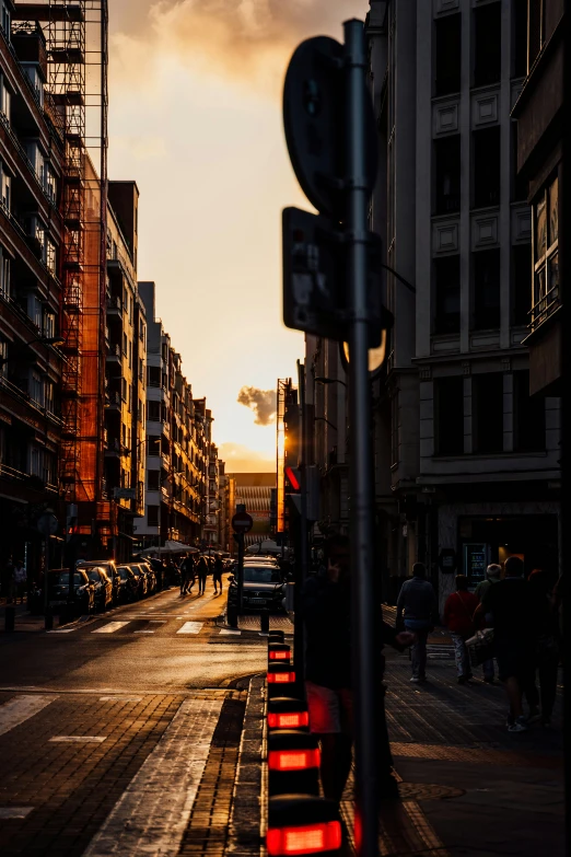 people and cars line a street as the sun sets