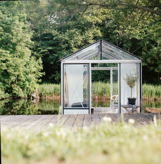 a porch sitting on a dock outside of a small glass house