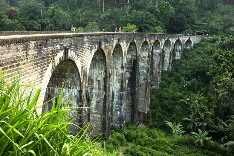 a old stone bridge spans a valley that stretches into the distance