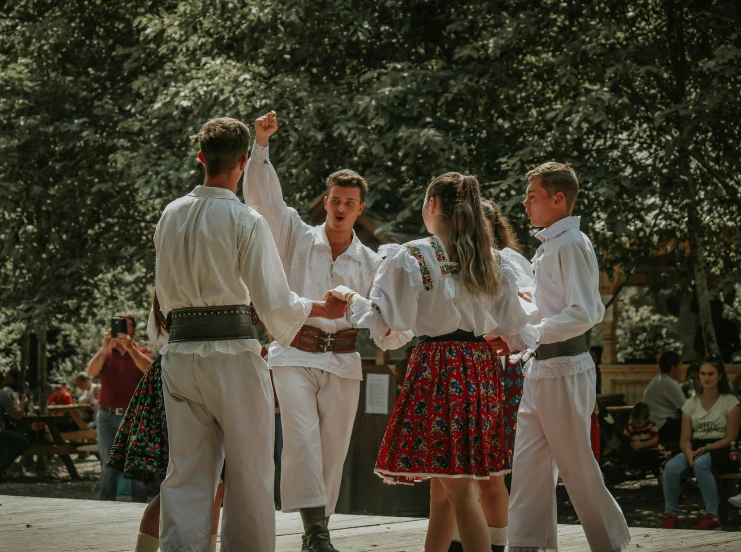 men in white clothes dancing in a forest