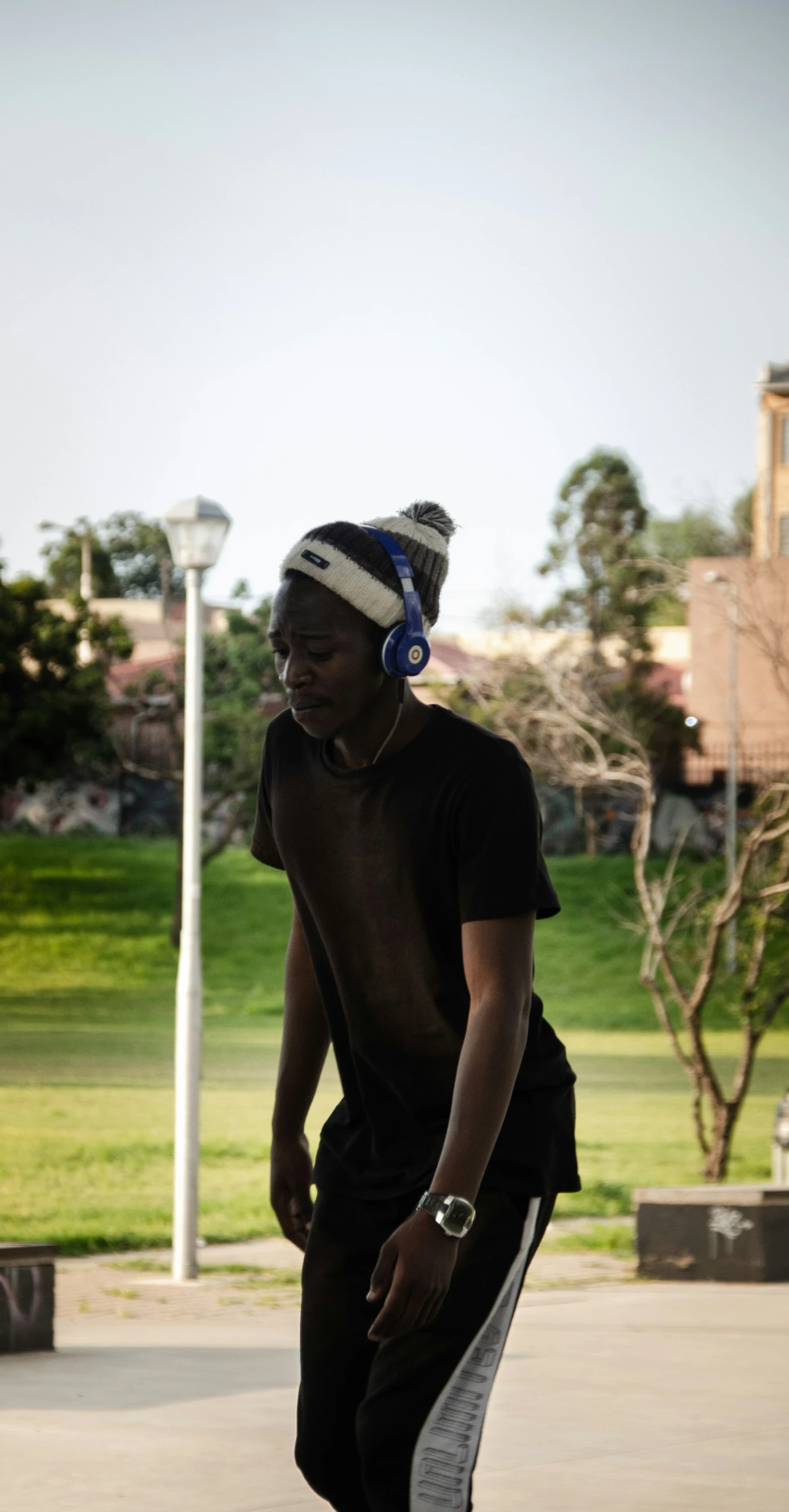 a man wearing headphones riding a skateboard on a sidewalk