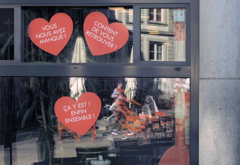 several red heart cutouts are on display in the window