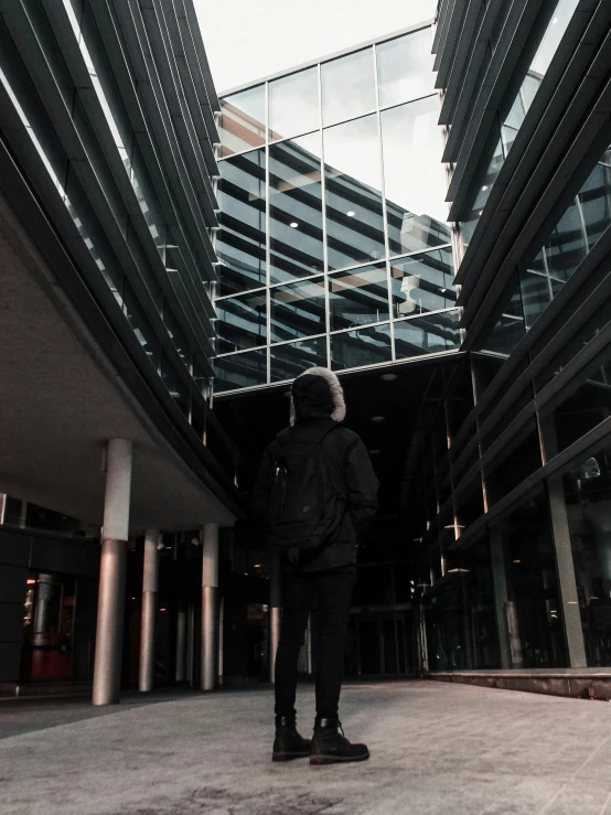 a woman stands outside a tall glass building