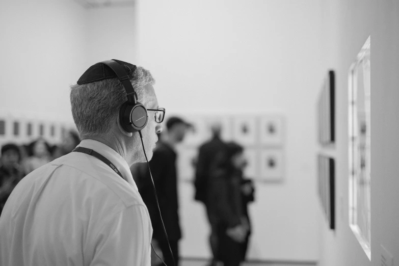 man with headphones looking at art work