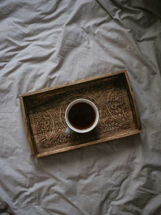 a cup of tea is sitting in an old wooden tray