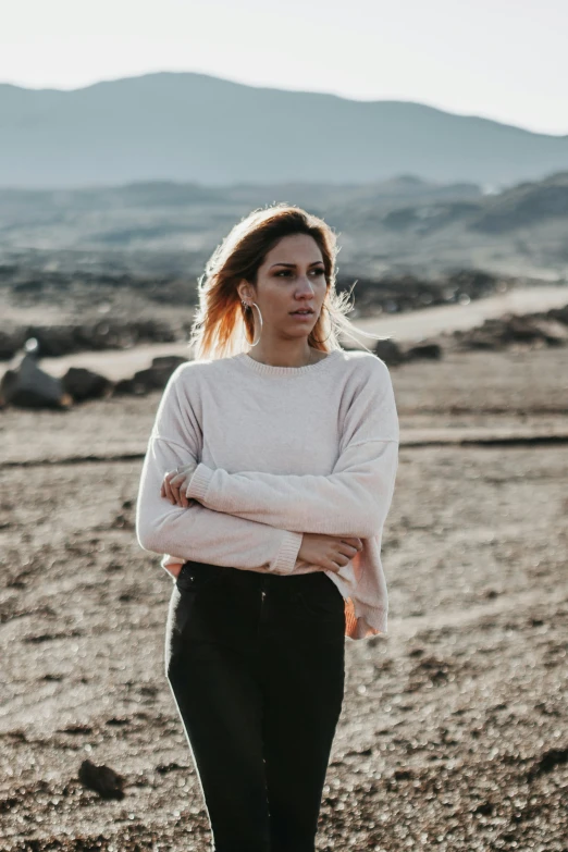 a woman with red hair stands in a barren field